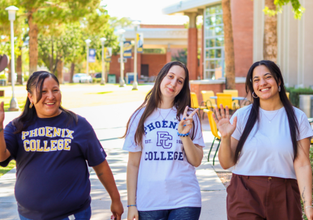 Three PC Ambassadors walking across campus waving